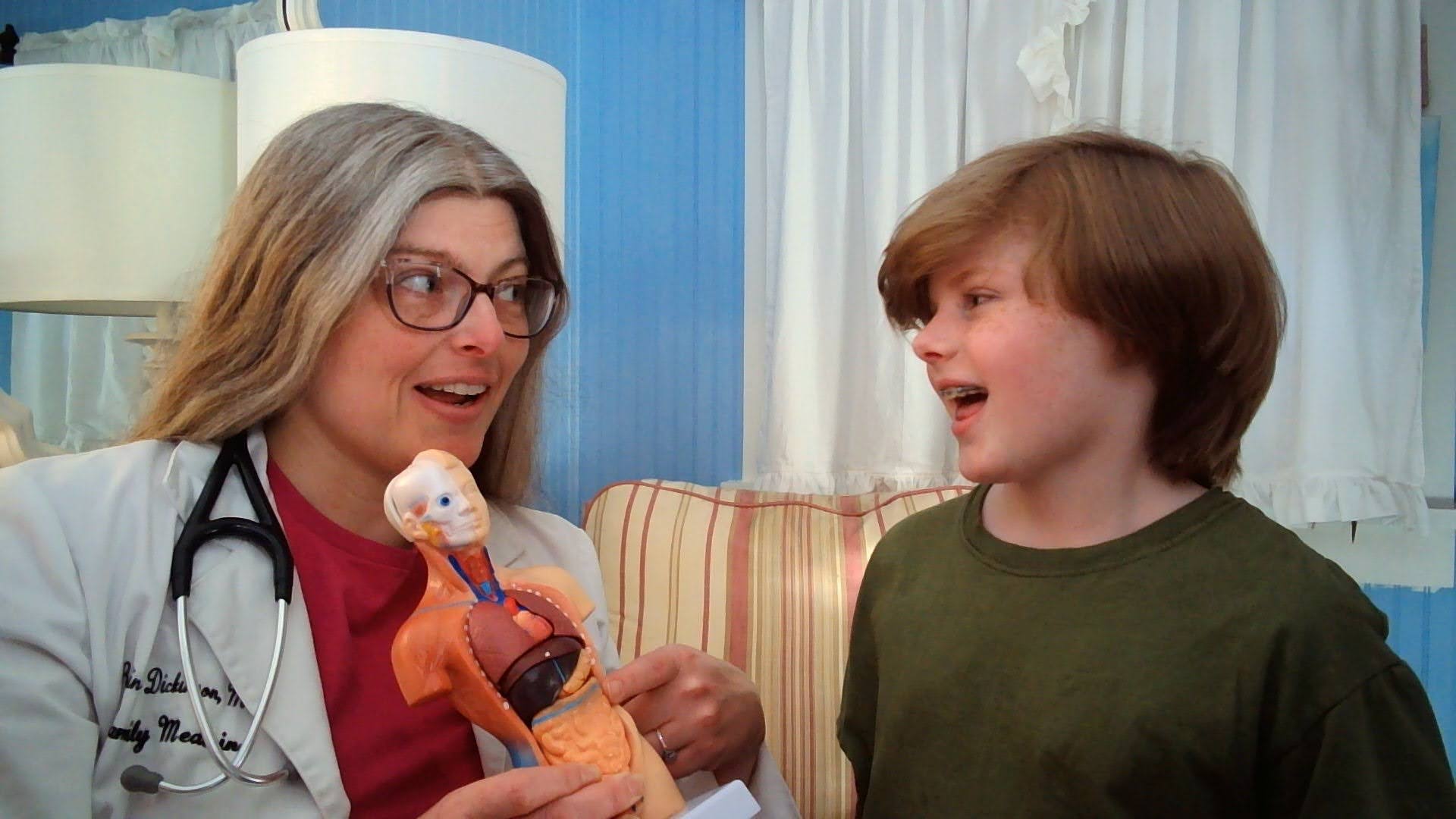 Dr. Robin teaching pre-med curriculum for kids who want to be doctors. She is holding a model of internal organs and talking animatedly with a tween.