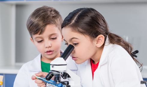 two kids in lab coats at microscope learning human anatomy for kids