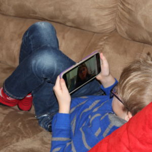 Child engaged in watching a LifePath lesson on a phone, learning human biology from Dr. Robin