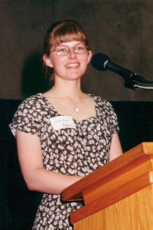 Dr. Robin Dickinson smiling while giving undergraduate scholarship speech at University of Denver 1998